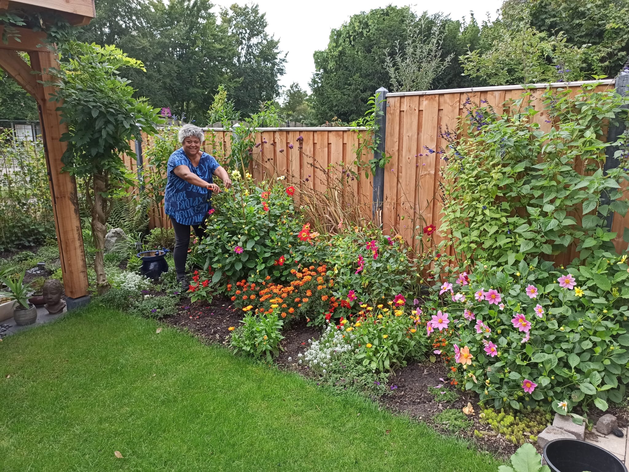 Aanleg en hout: kleurrijke tuin met overkapping in samenwerking met Tuinpraktijk De Groene Loods