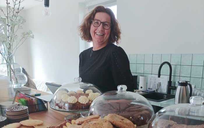 "Gastvrije vrijwilliger serveert koffie en thee in een knus Theehuis, terwijl bezoekers ontspannen genieten van een gezellige sfeer."