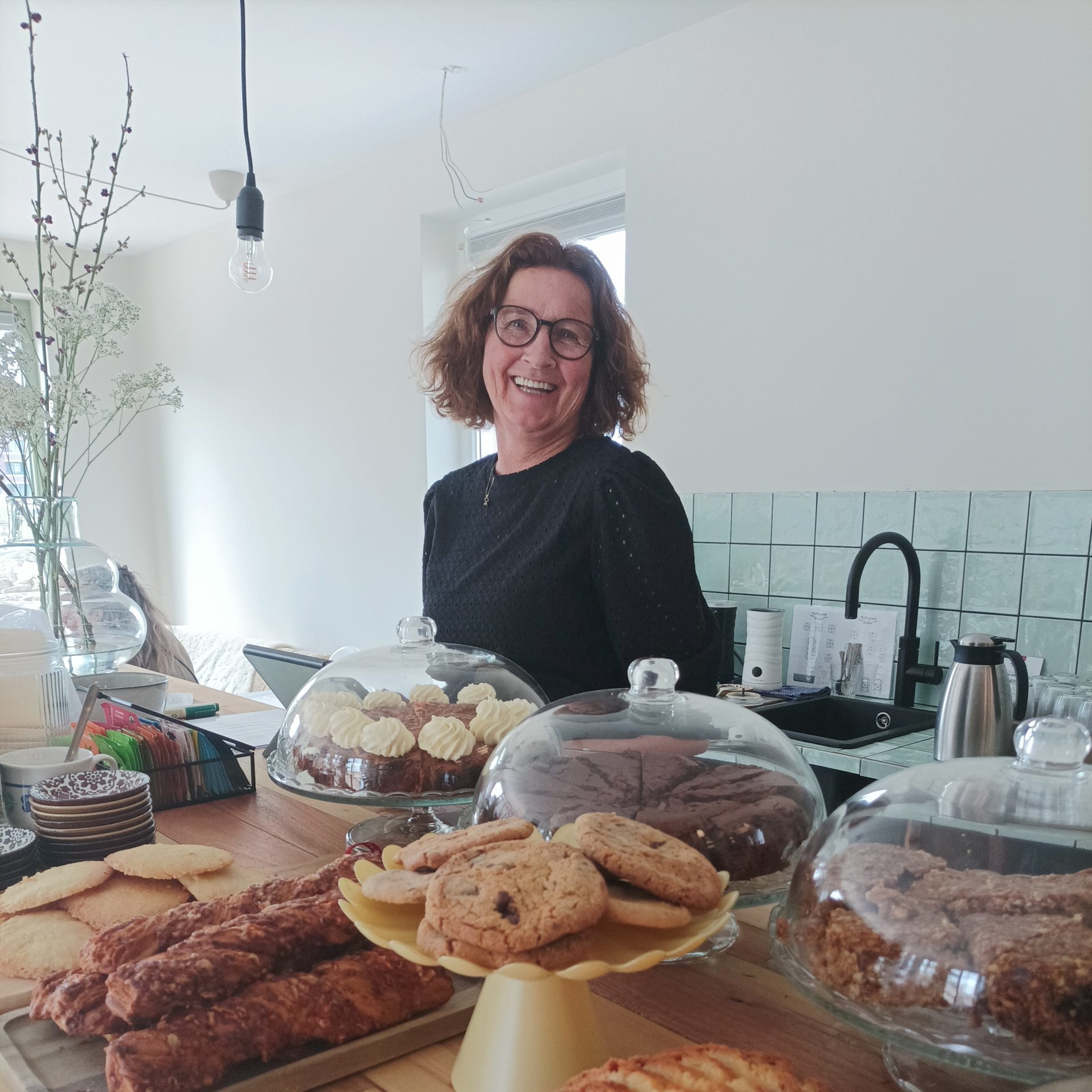 "Gastvrije vrijwilliger serveert koffie en thee in een knus Theehuis, terwijl bezoekers ontspannen genieten van een gezellige sfeer."