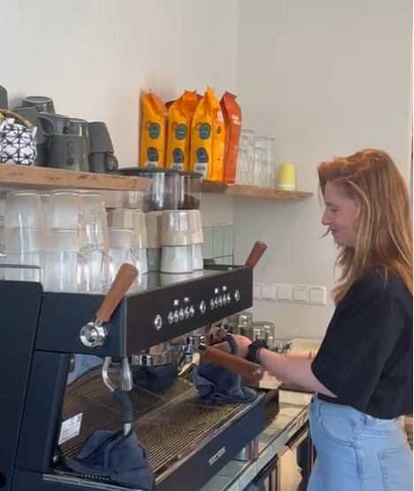 Brenda schenkt koffie in het Theehuis van Land in Zicht terwijl gasten ontspannen aan tafel zitten.